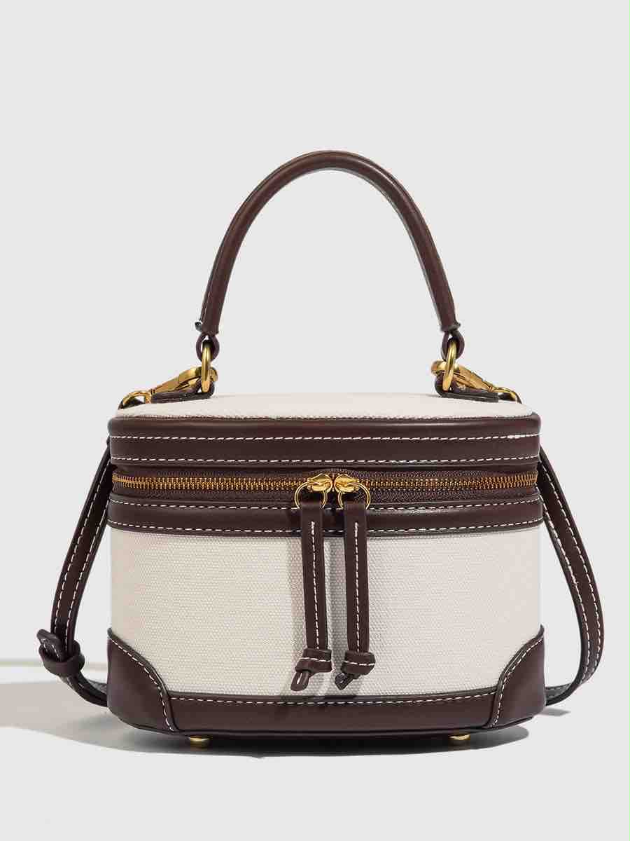 The Belle Bag, a structured top-handle bag in cream canvas and brown leather